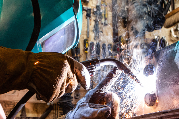 Pressenbau-Schmiedetechnik Schweißer mit Schutzmaske bei der Arbeit. Symbolbild für Verbindungselemente und Sonderschrauben der Stahlberg GmbH im Pressenbau und in der Schmiedetechnik.