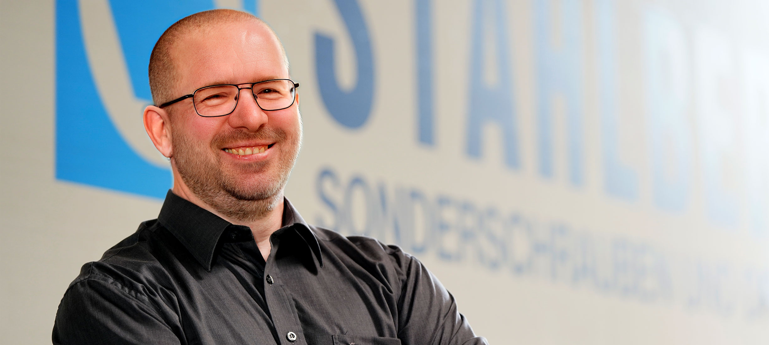 Thomas Hilgart – Prokurist & Leiter Qualitätssicherung bei der Stahlberg GmbH Thomas Hilgart, Prokurist und Leiter Qualitätssicherung der Stahlberg GmbH, steht vor dem Firmenlogo – Symbol für Präzision, Qualität und verlässliche Beratung